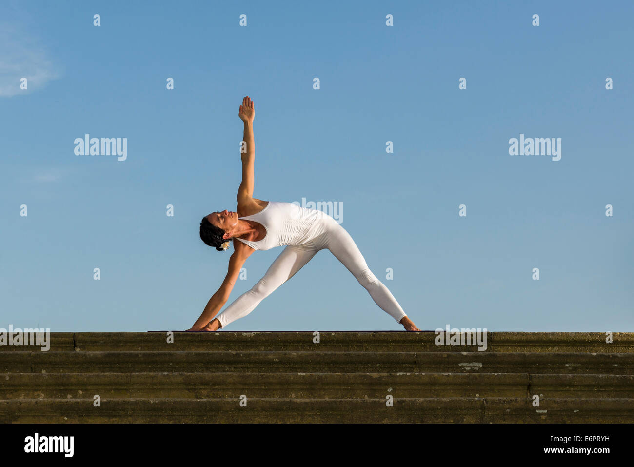 Jeune femme la pratique de l'Hatha Yoga, à l'extérieur, montrant la pose Trikonasana, Triangle Banque D'Images