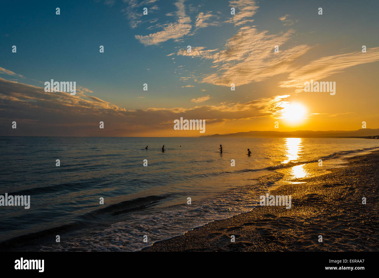 Silhouette de quatre garçons jouant avec une balle dans la mer à la fin de la journée Banque D'Images
