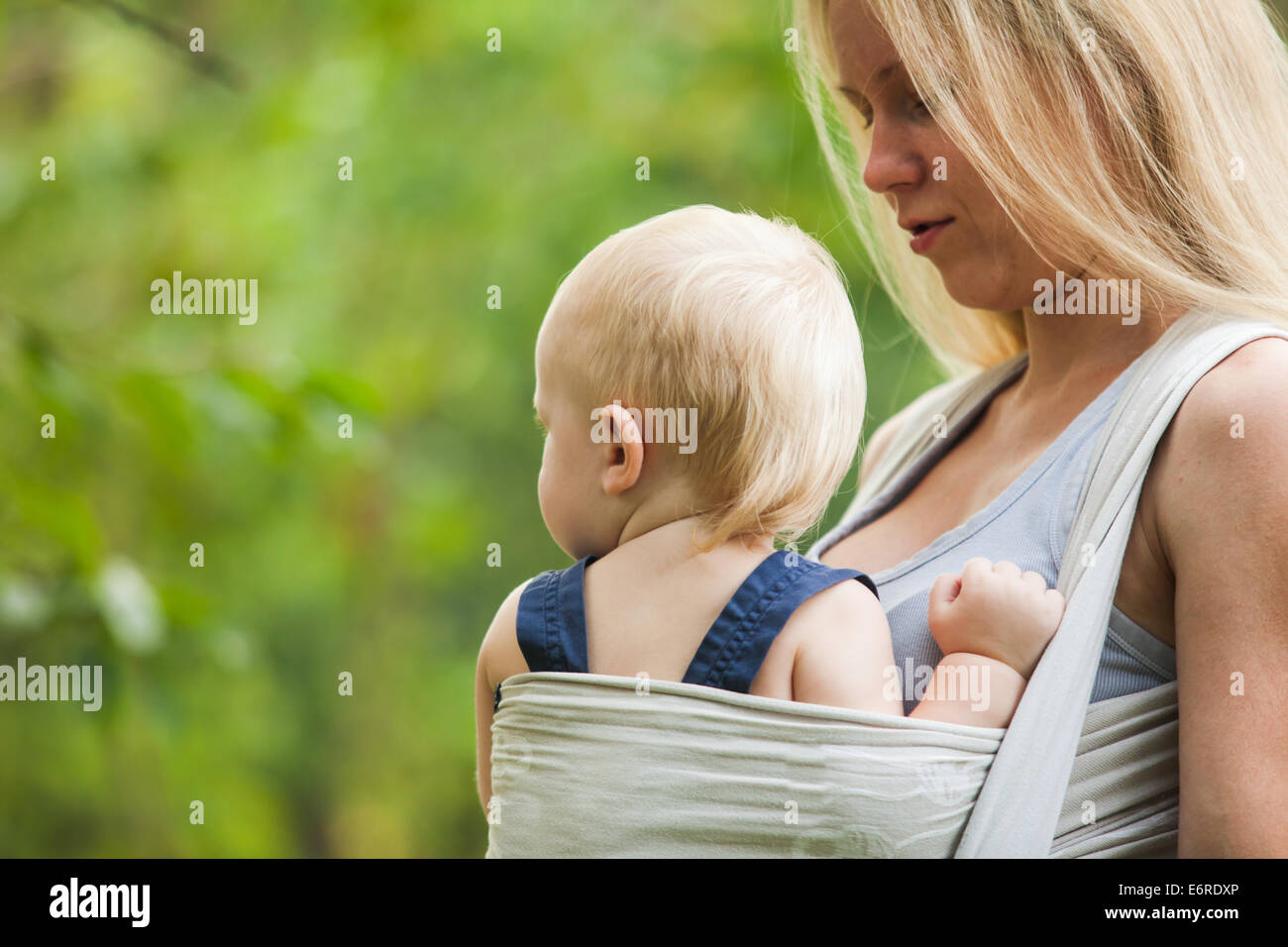 La mère est l'accomplissement de son enfant et la marche à pied. Bébé dans une écharpe. Banque D'Images