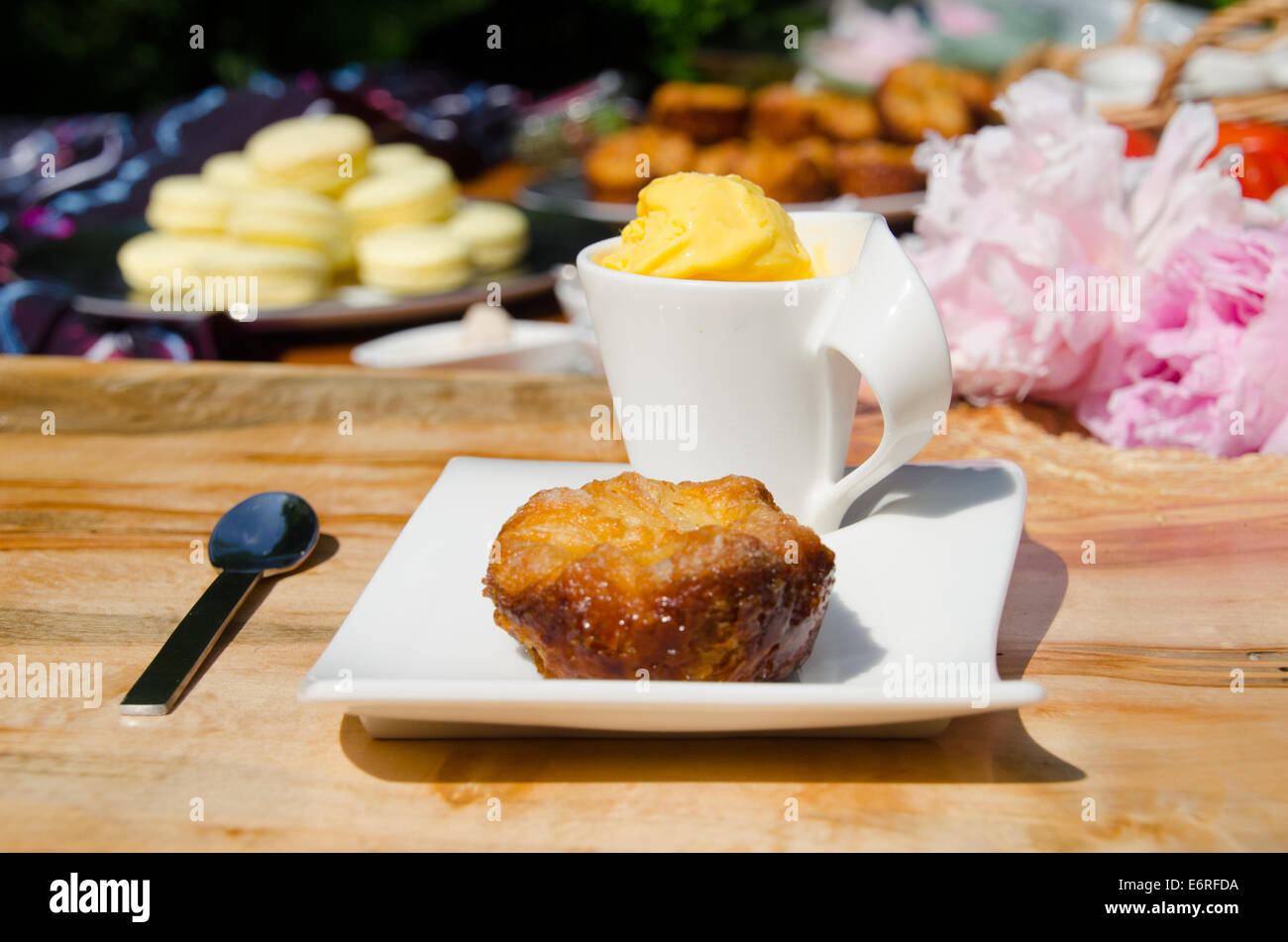 Sur une plaque à pâtisserie avec une tasse de sorbet au citron, avec plus de pâtisseries comme les macarons et muffins dans l'arrière-plan de la scène de pique-nique Banque D'Images
