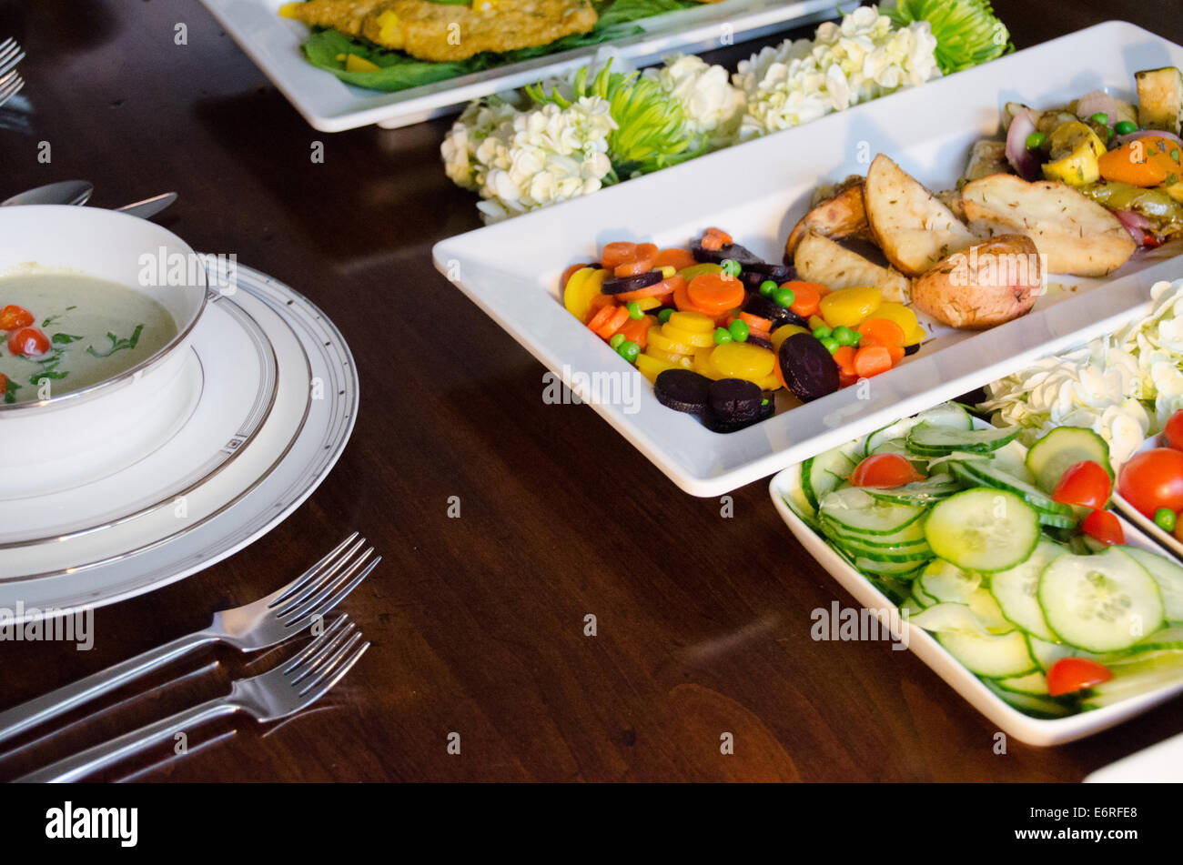 Gros plan d'un style buffet dîner de style familial sur une table de salle à manger avec le poisson, la soupe, les pommes de terre et légumes Banque D'Images