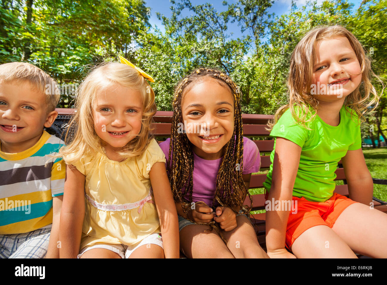 Quatre enfants sur le banc dans le parc Banque D'Images