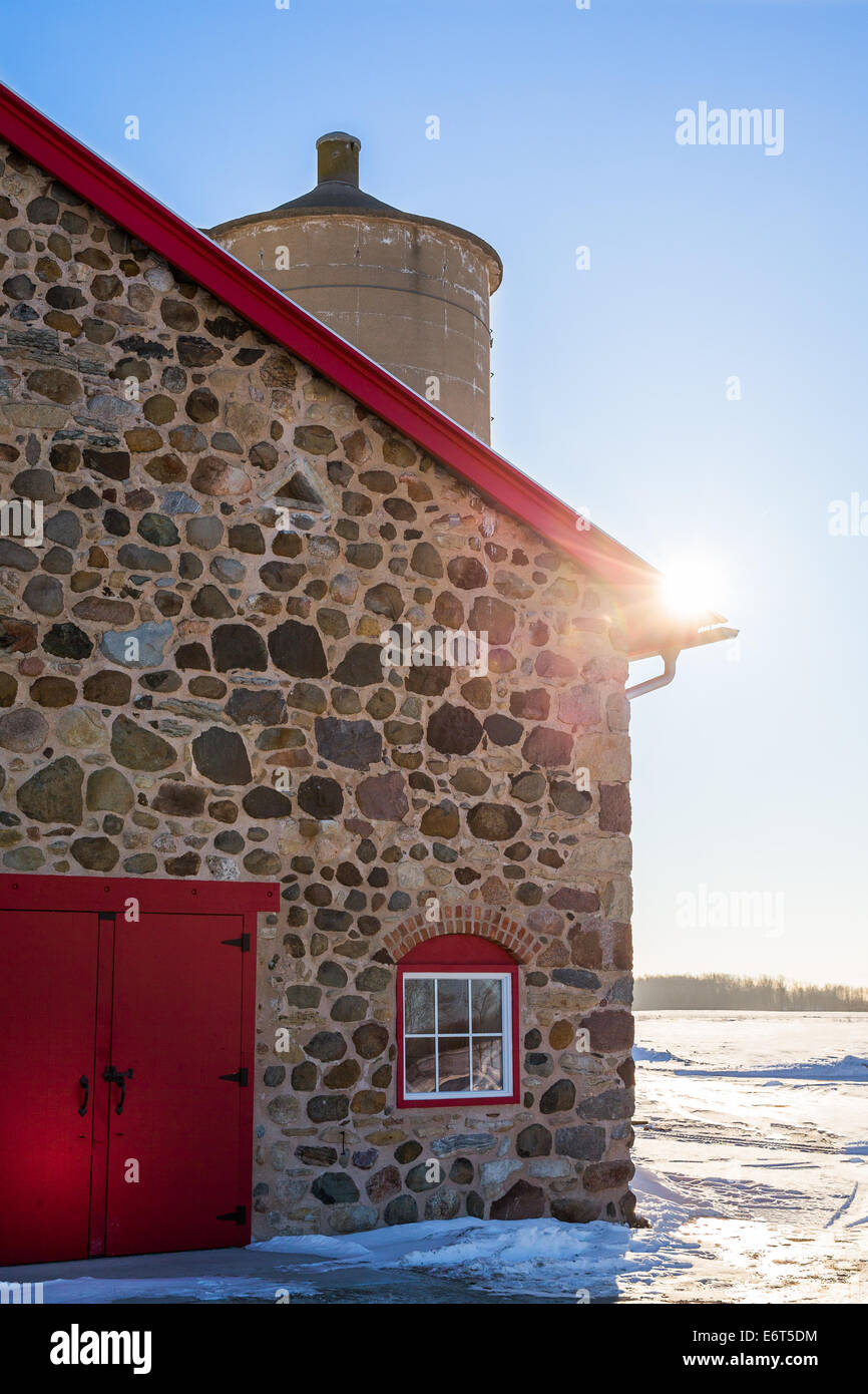 Ancienne grange en pierre vers 1903. Scène d'hiver. La lumière du soleil chaud et bien arrondi. Porte et fenêtre rouge vif avec brique arch. Banque D'Images