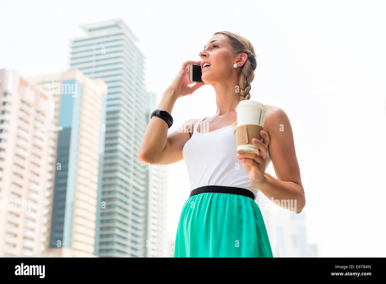 Jeune femme téléphoner avec un téléphone mobile, de boire du café dans l'agglomération de la ville Dubai Banque D'Images
