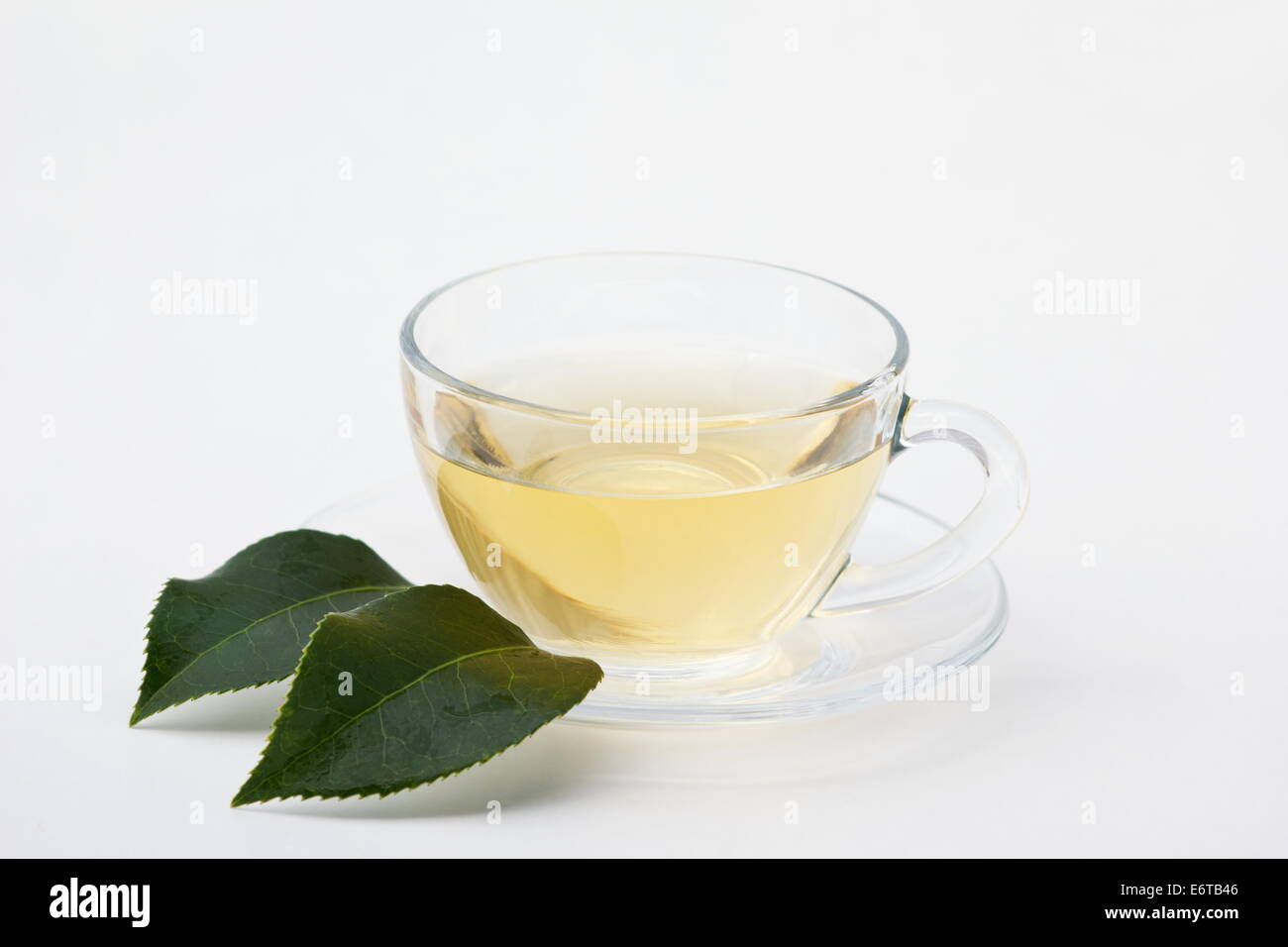 Le thé vert dans une tasse en verre sur fond blanc Banque D'Images