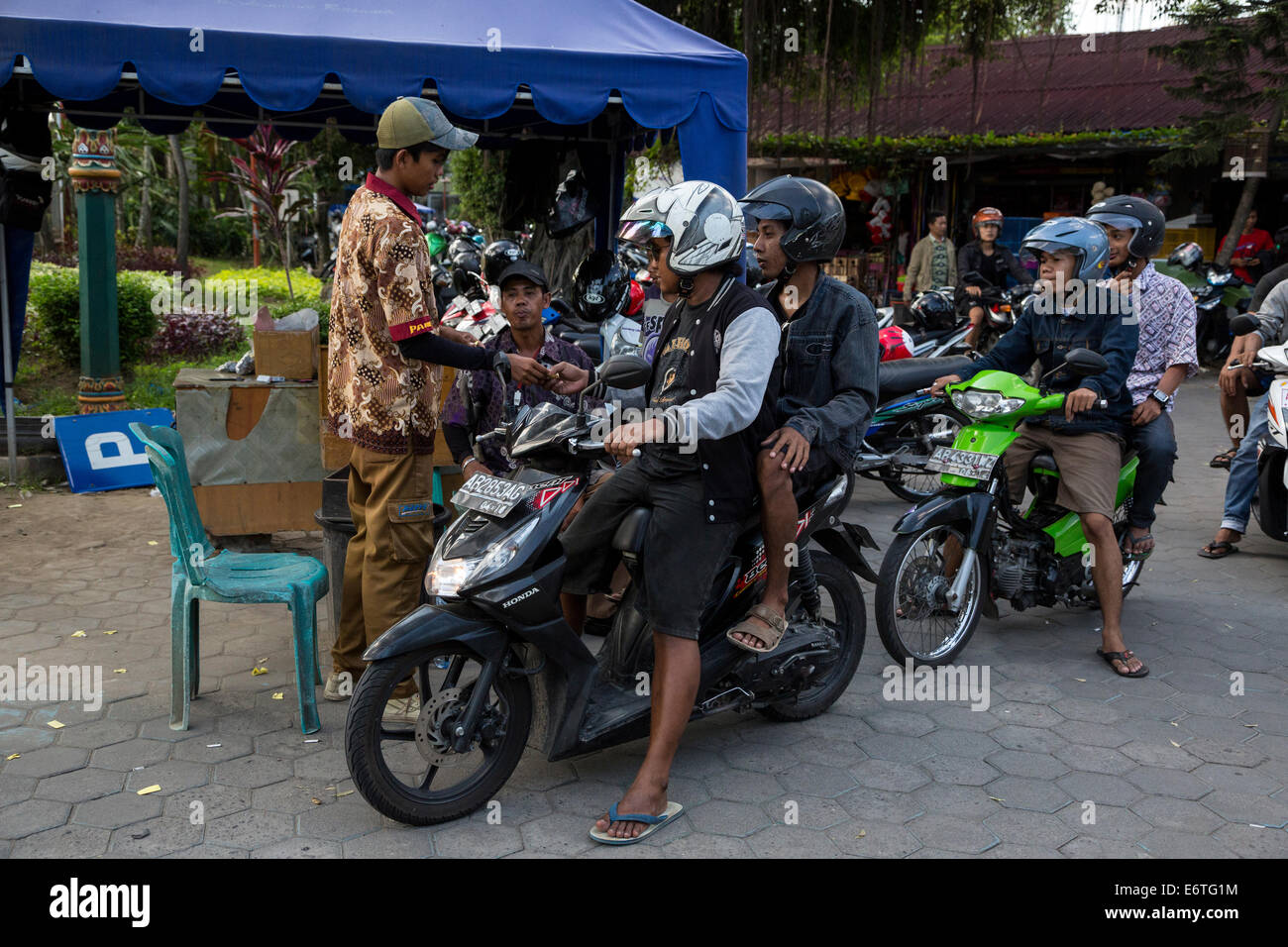 Yogyakarta, Java, Indonésie. Payer les frais de stationnement avant de quitter le Parking moto au marché aux oiseaux. Banque D'Images