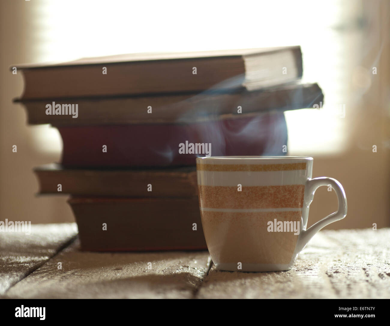 Tasse de café et des tas de livres sur l'ancien fond de bois blanc et fenêtre avec stores. Banque D'Images