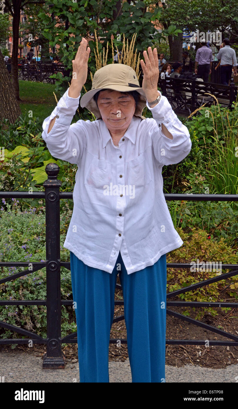 Une vieille femme chinoise Falun Dafa en exercices pratiques Suare Union Park à New York. C'est la position debout de Falun. Banque D'Images