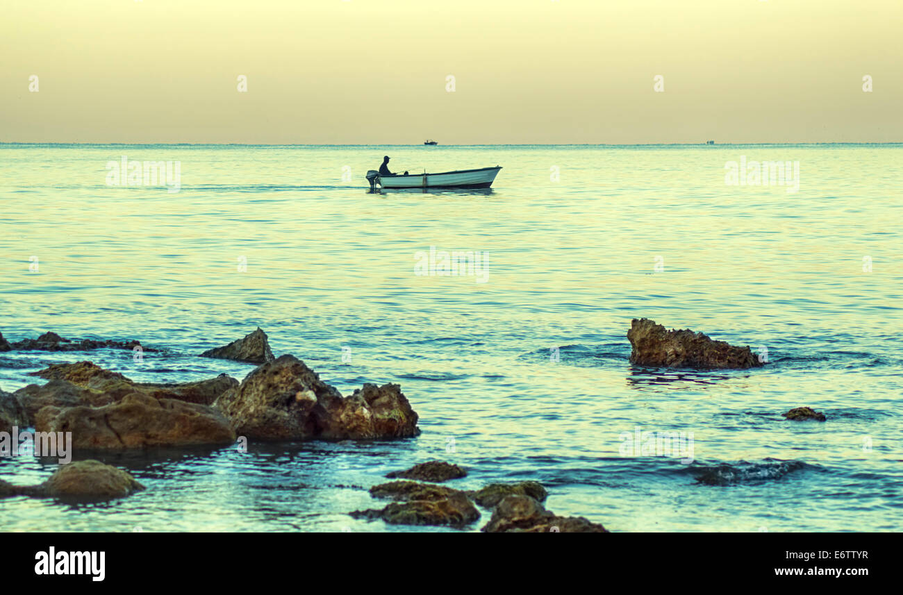 Silhouette d'un pêcheur solitaire dans la mer calme. Banque D'Images