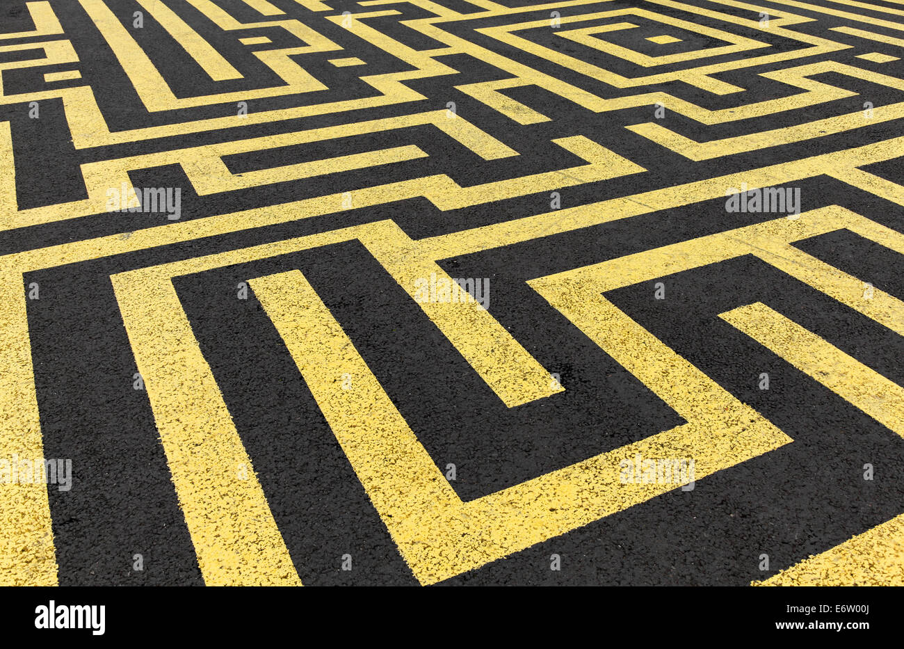 Labyrinthe jaune peinte sur une route d'asphalte noir Banque D'Images