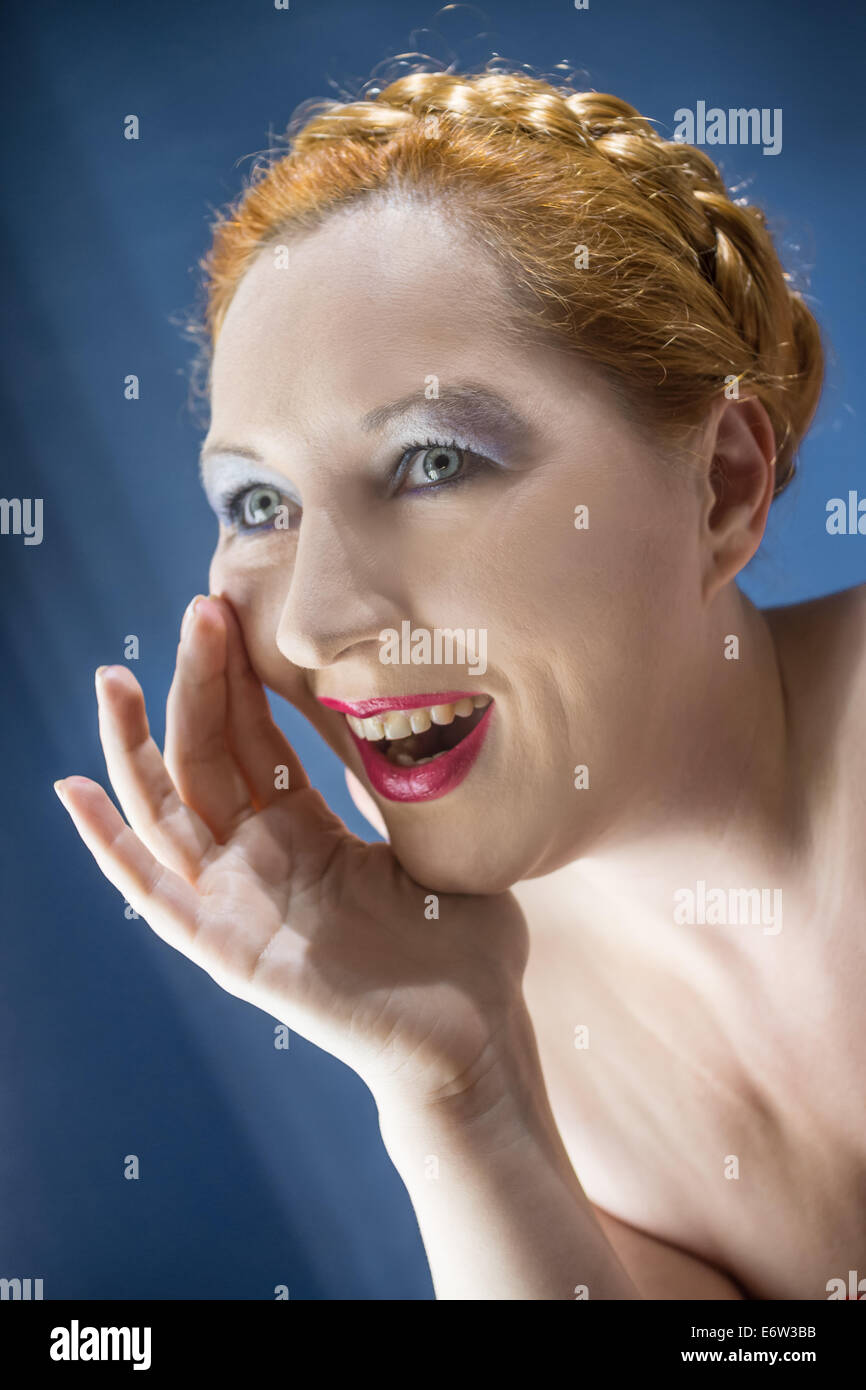 Le red-haired woman hurle mettre la main à la bouche Banque D'Images