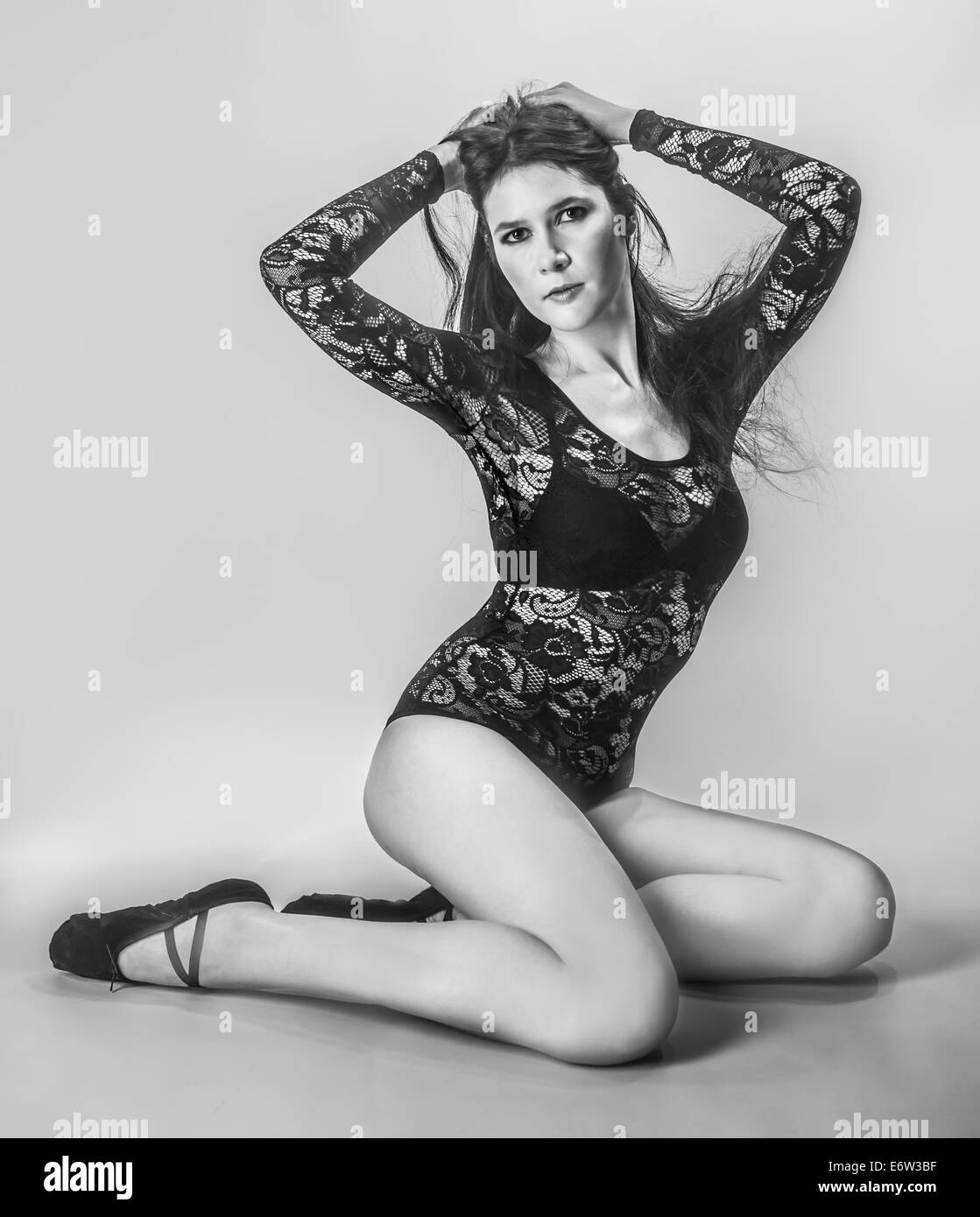 Le noir et blanc photo d'une belle fille de mode avec de belles jambes assis vêtu d'une robe en dentelle Banque D'Images