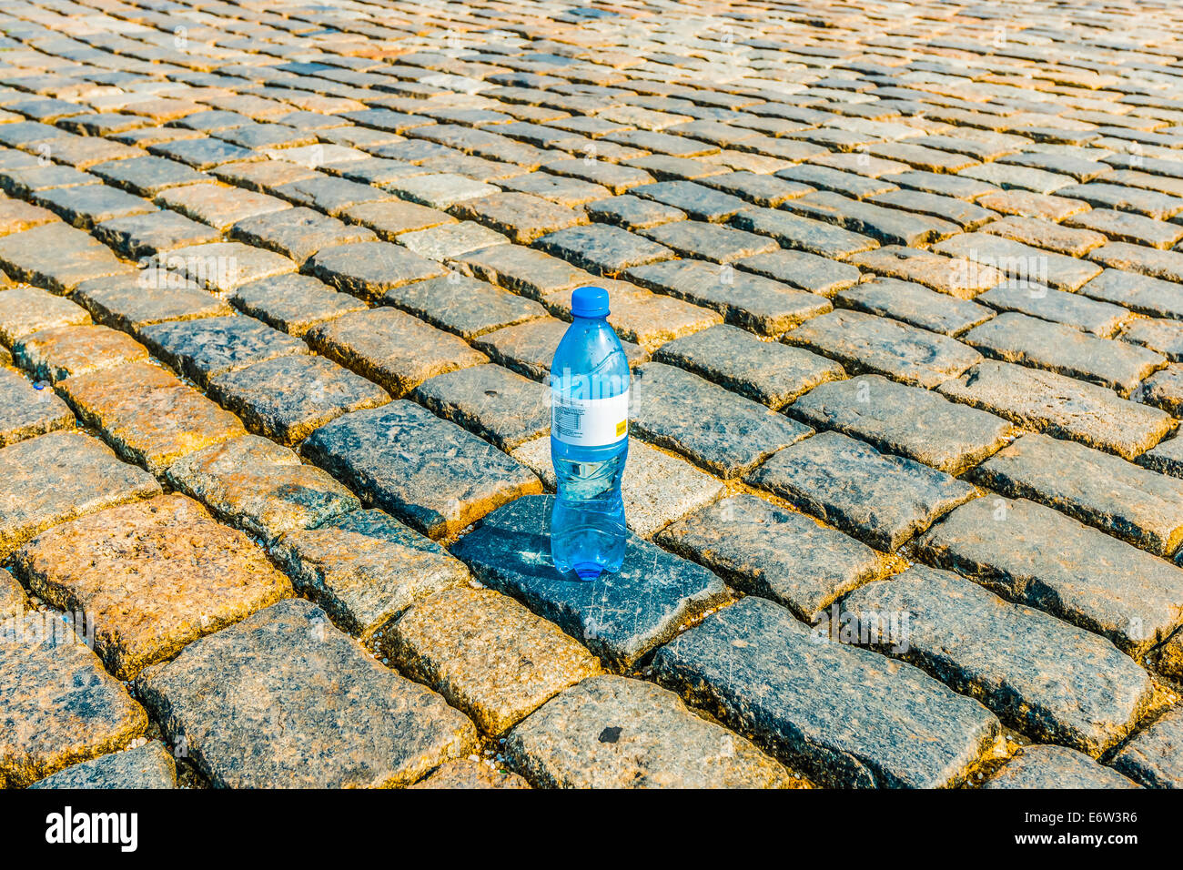 Lonely bouteille de l'eau potable claire sur le sol pavé de galets torride Banque D'Images