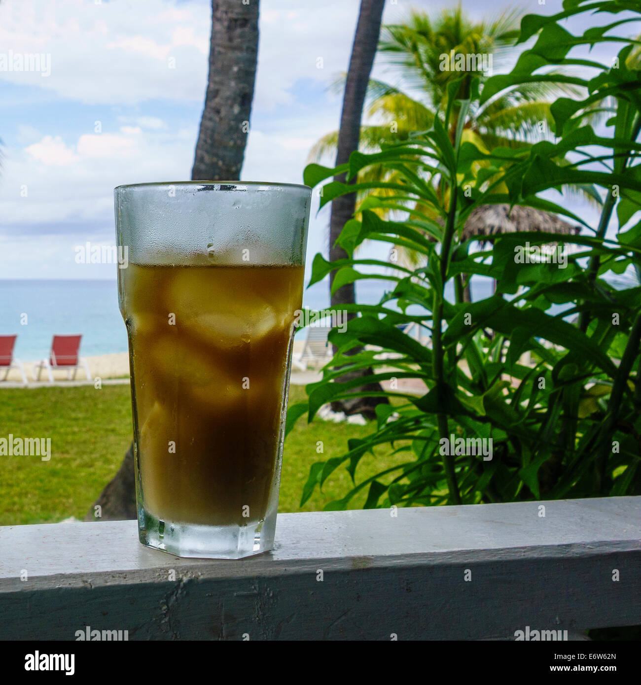 Un verre de thé glacé se trouve sur un balcon balustrade surplombant la mer des Caraïbes sur l'île de Sainte-Croix, Îles Vierges des États-Unis. Banque D'Images