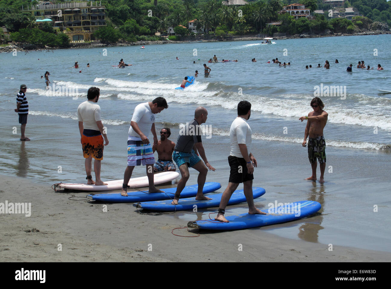 Les hommes debout sur les planches sur la plage pendant une leçon de surf à Sayulita, Mexique. Banque D'Images