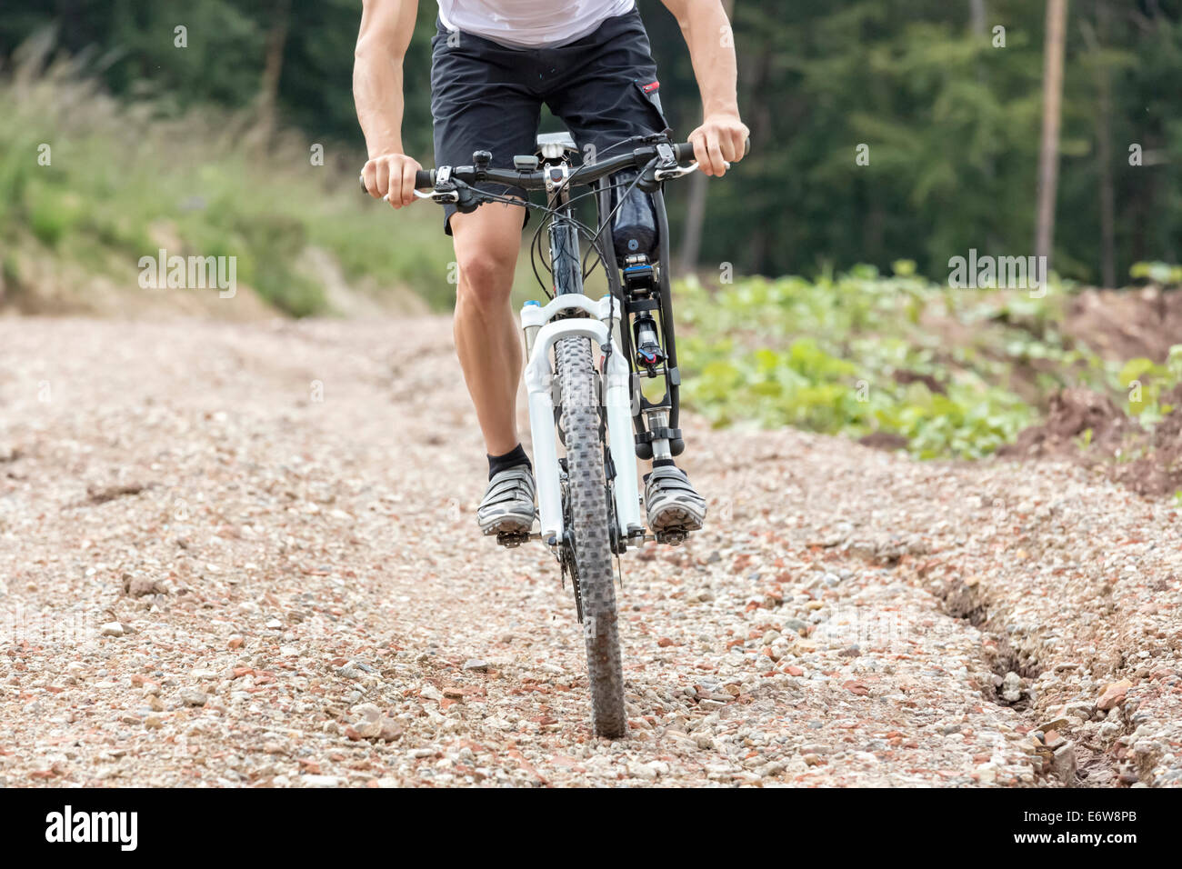 Mountain bike rider avec prothèse de jambe conduit une piste de gravier Banque D'Images