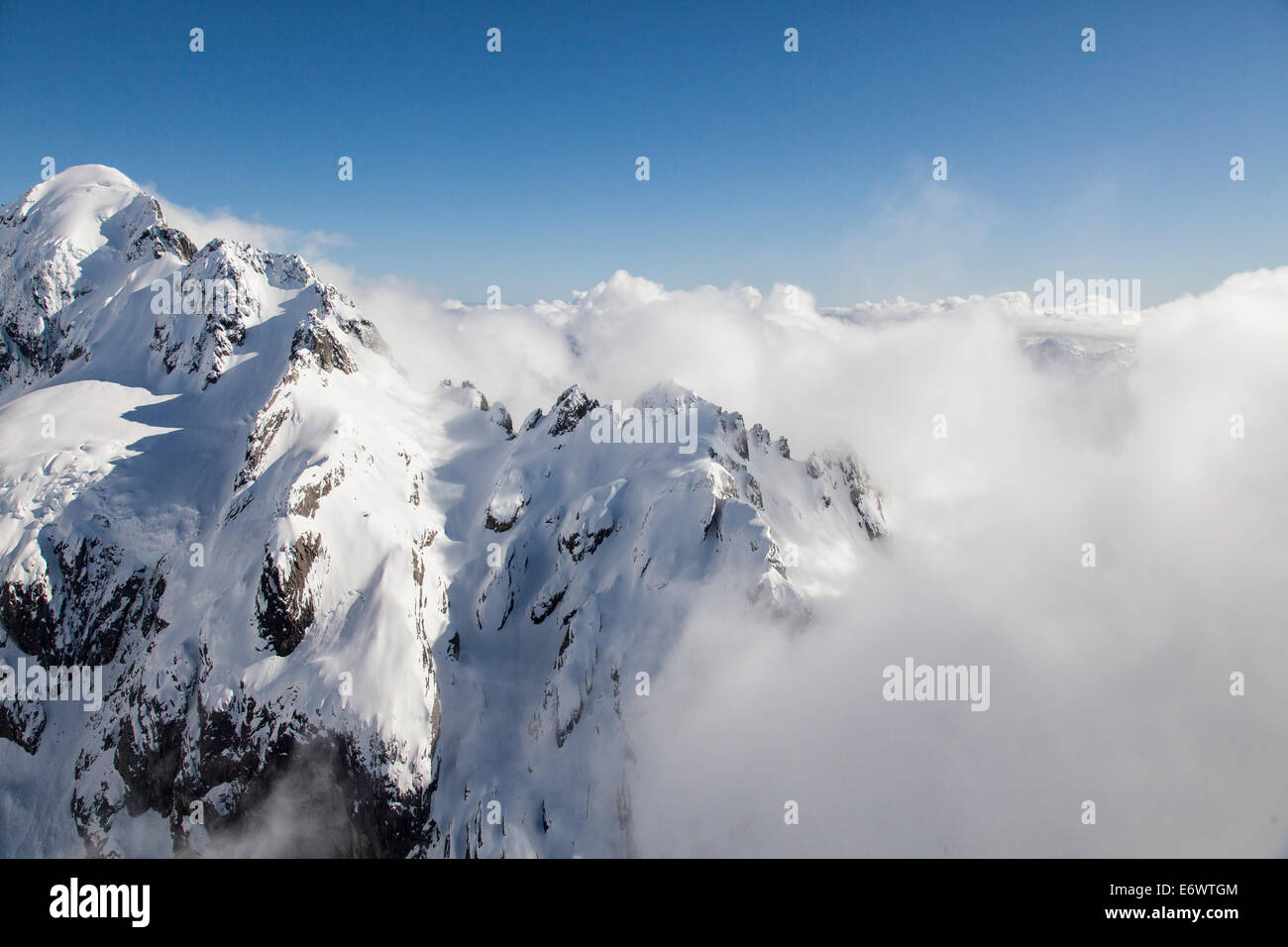 Vol en hélicoptère au-dessus des montagnes enneigées de nuages bas, gamme Bryneira, Alpes du Sud, l'île du Sud, Nouvelle-Zélande Banque D'Images