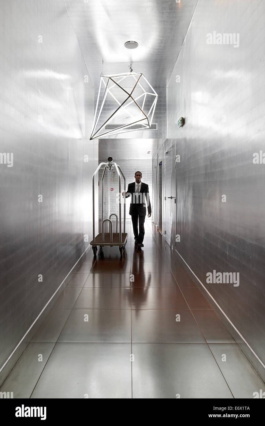 Commis d'hôtel dans le couloir avec des murs couverts d'argent dans l'aluminium, l'Hôtel La Maison Champs Elysées, conçu par Martin Margiela, Banque D'Images