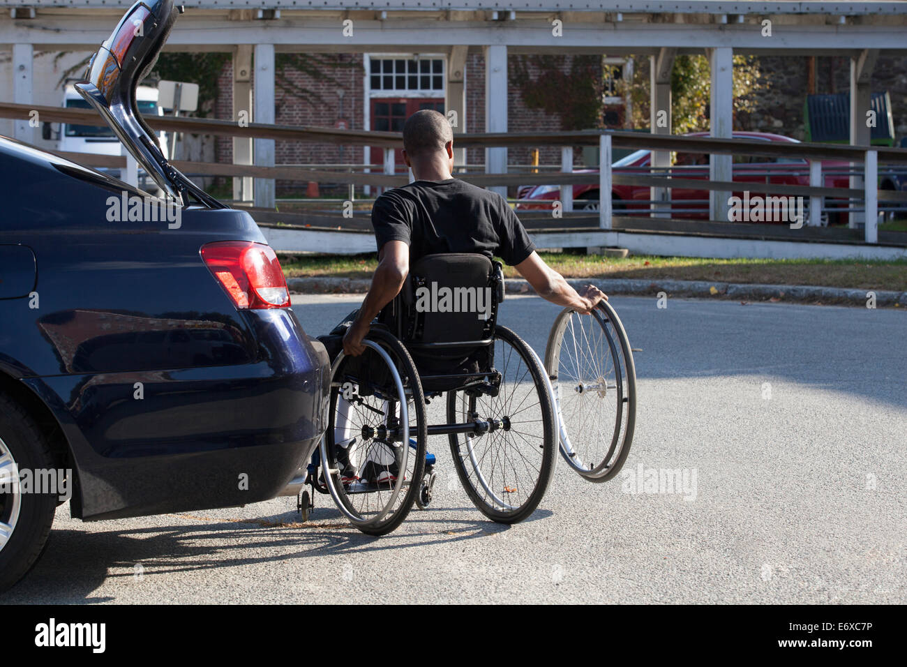 L'homme avec la méningite en entrant dans son fauteuil roulant accessible véhicule Banque D'Images