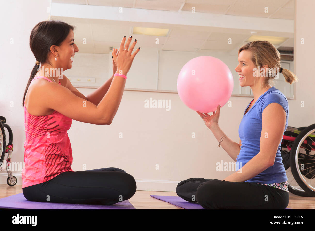 Les jeunes femmes ayant une lésion de la moelle épinière en jouant avec une boule d'exercice Banque D'Images