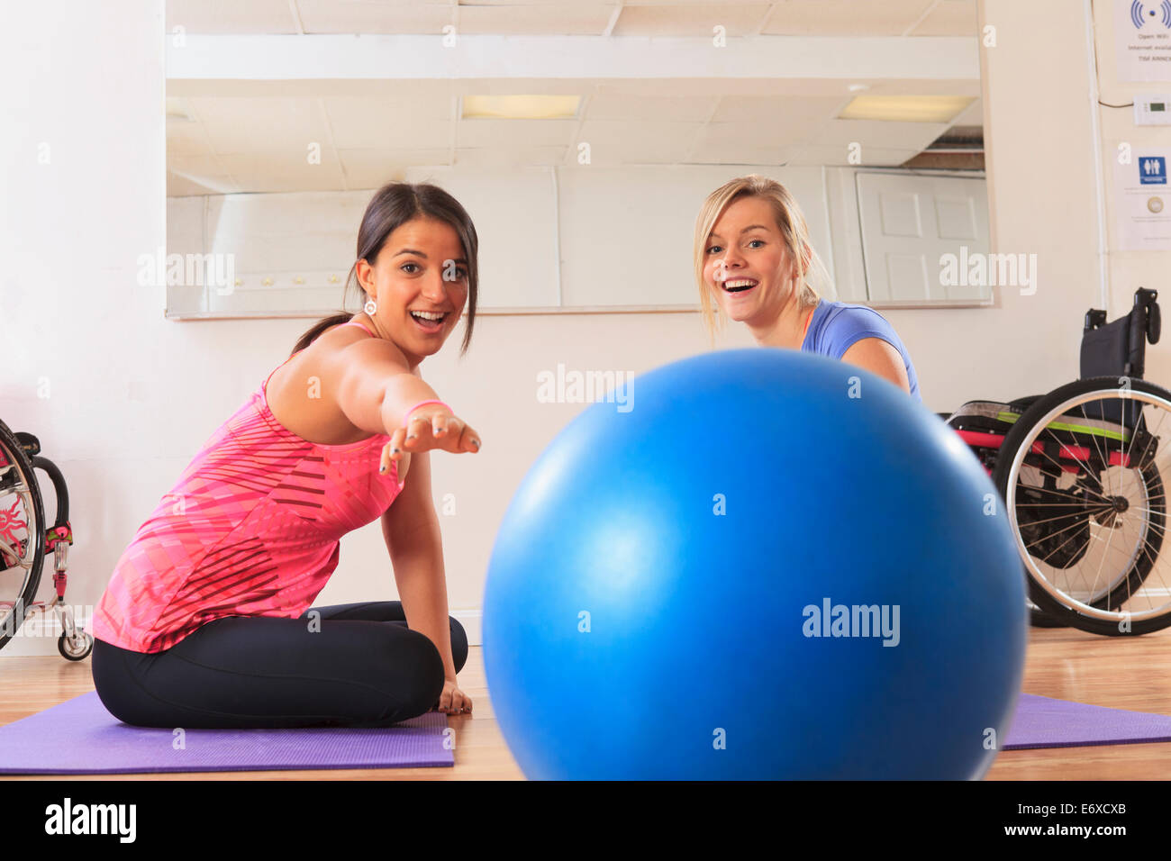 Les jeunes femmes ayant une lésion de la moelle épinière en jouant avec une boule d'exercice Banque D'Images