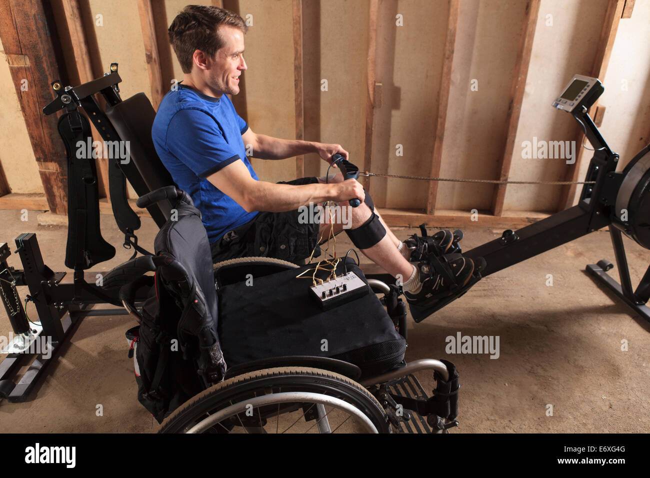 L'homme avec de la moelle épinière à l'aide de sa machine à ramer avec un stimulateur musculaire attaché Banque D'Images