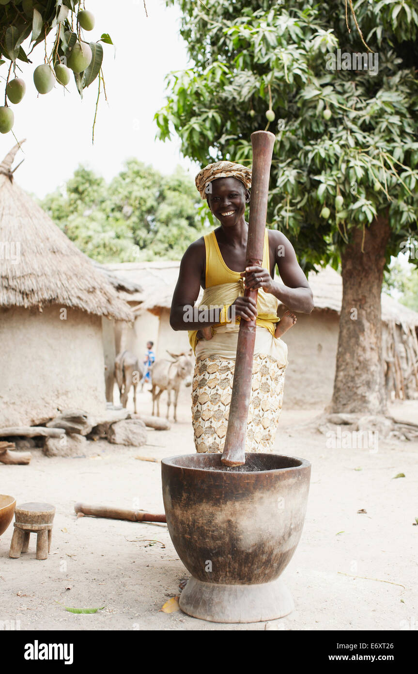 Femme portant sur l'enfant retour à la farine de maïs de meulage, Magadala, Mali Banque D'Images