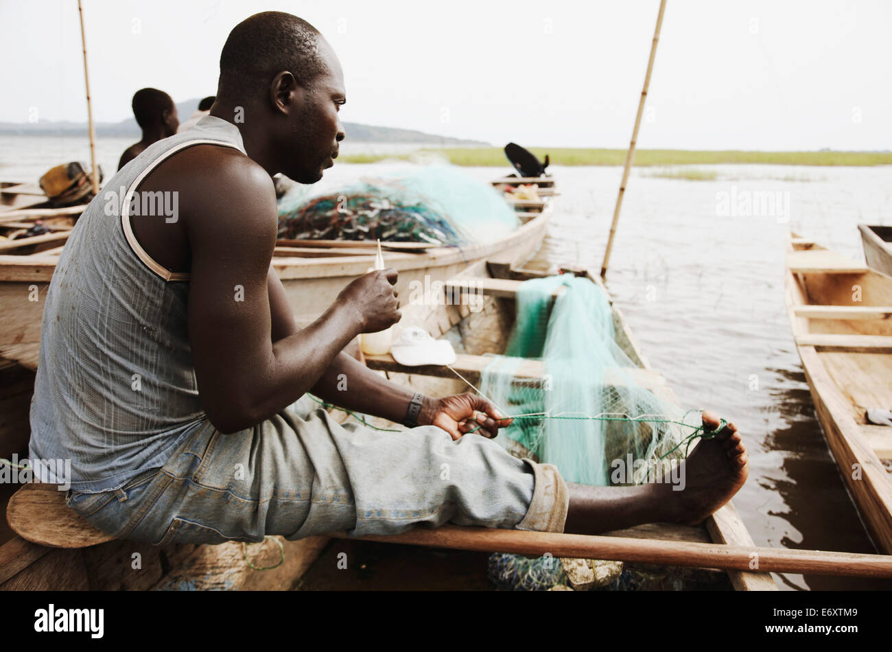 La réparation des filets de pêche pêcheur, le Lac Volta, au Ghana, District Asuogyaman Banque D'Images