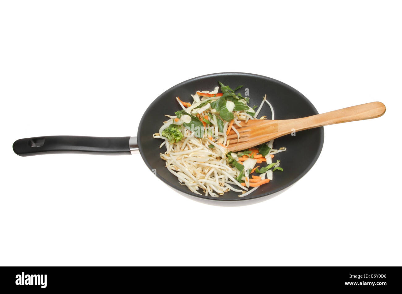 Faire sauter les légumes et les germes de soja dans un wok avec une spatule en bois isolés contre white Banque D'Images