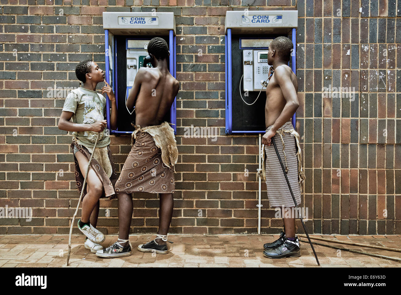Trois jeunes hommes de la tribu à une cabine téléphonique portant des vêtements traditionnels, Swaziland, Afrique Banque D'Images