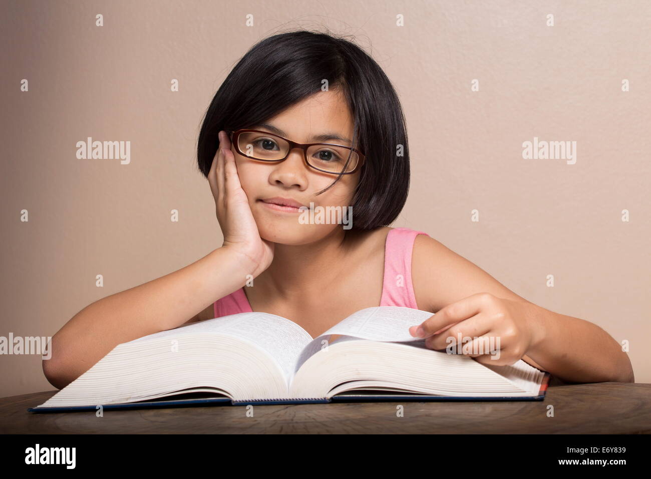 Jeune fille portant des lunettes la lecture à la maison Banque D'Images