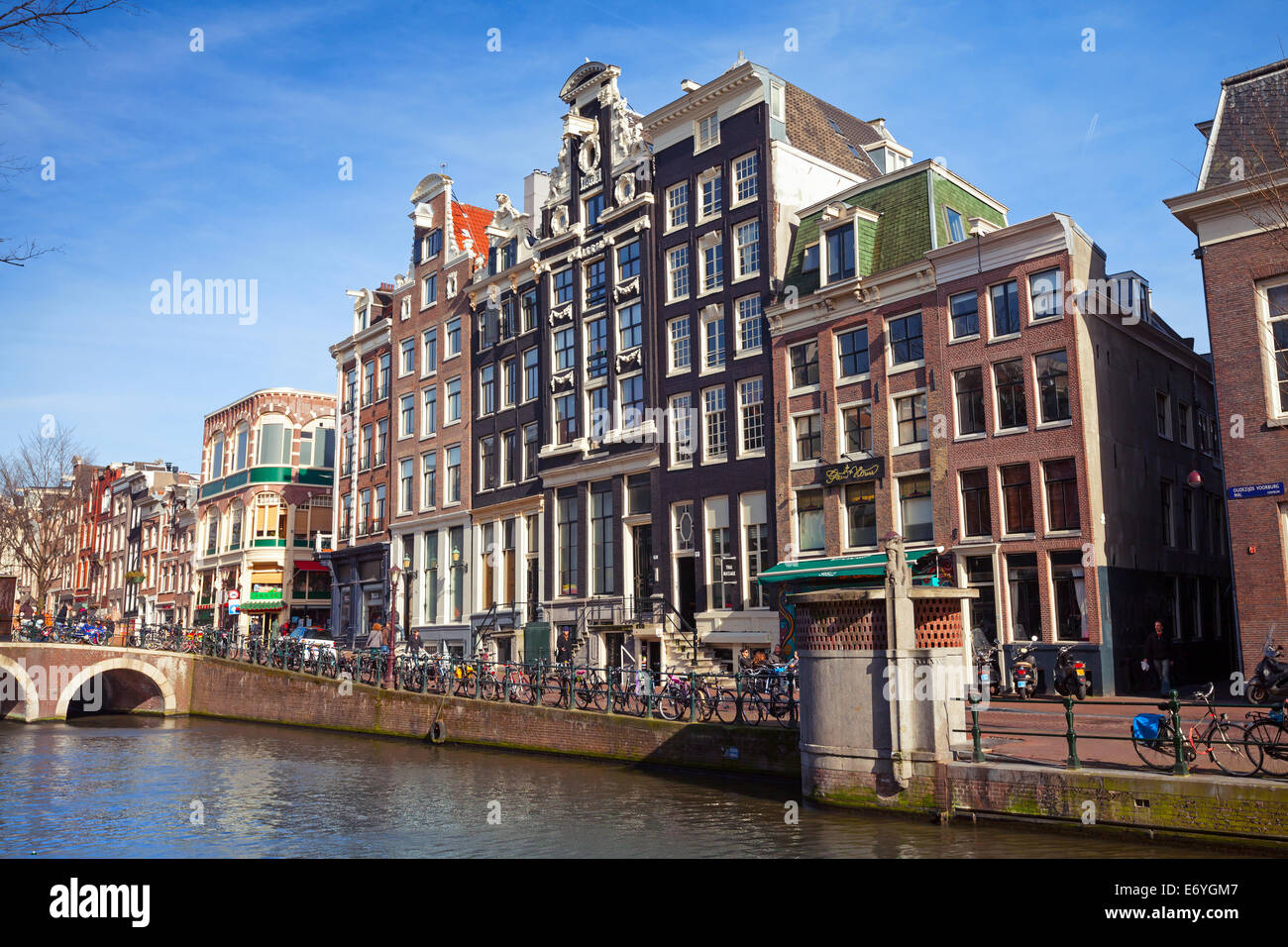 AMSTERDAM, Pays-Bas - 19 mars 2014 : maisons colorées sur la berge du canal au printemps journée ensoleillée. Les gens ordinaires à pied Banque D'Images