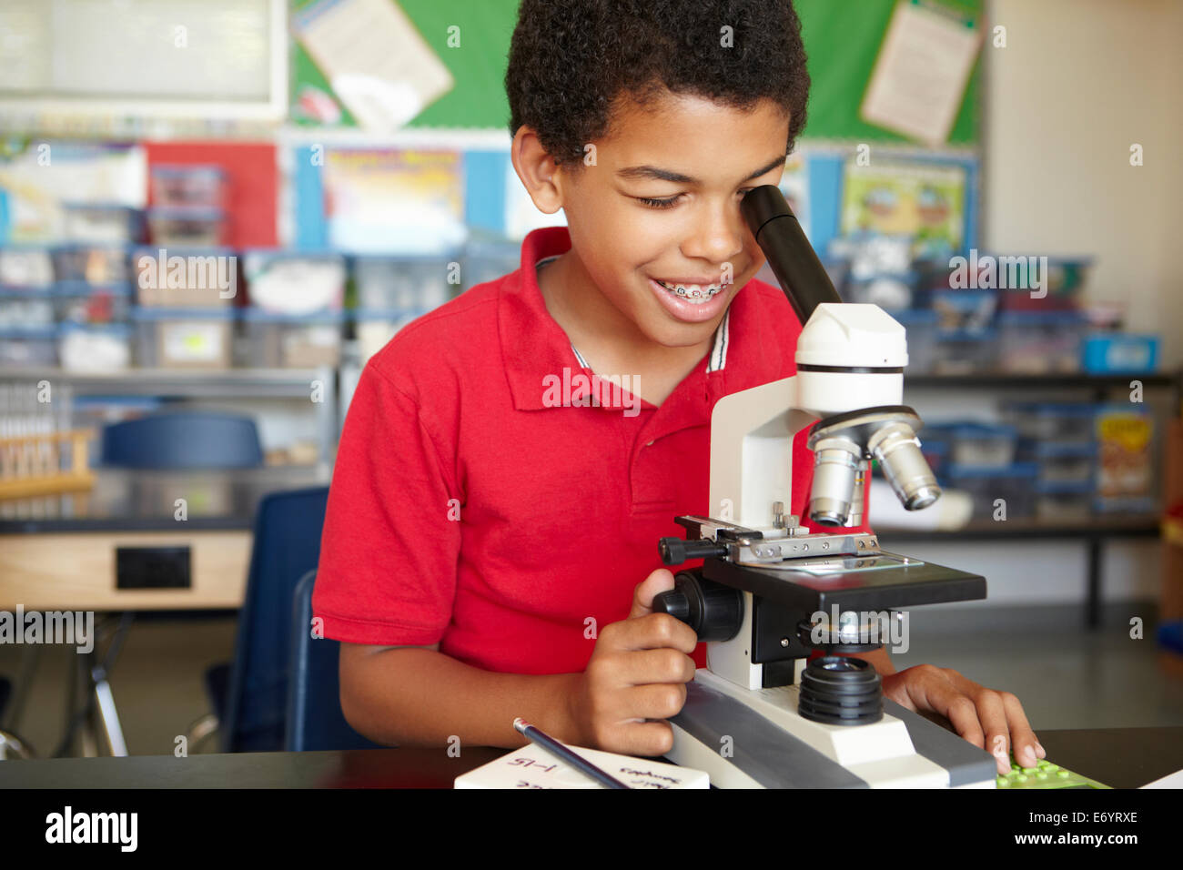 Garçon dans la classe de sciences avec microscope Banque D'Images