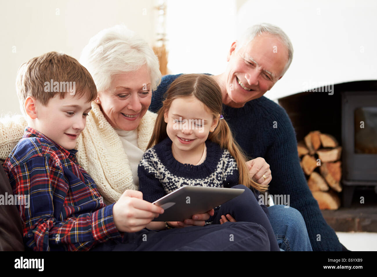 Les grands-parents Using Digital Tablet On Sofa avec petits-enfants Banque D'Images