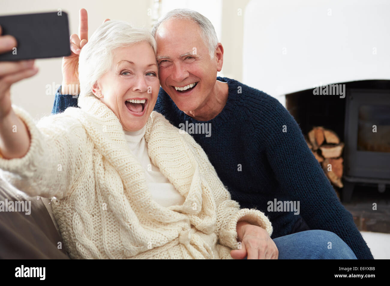 Senior Couple Sitting on Sofa prenant Selfies Banque D'Images