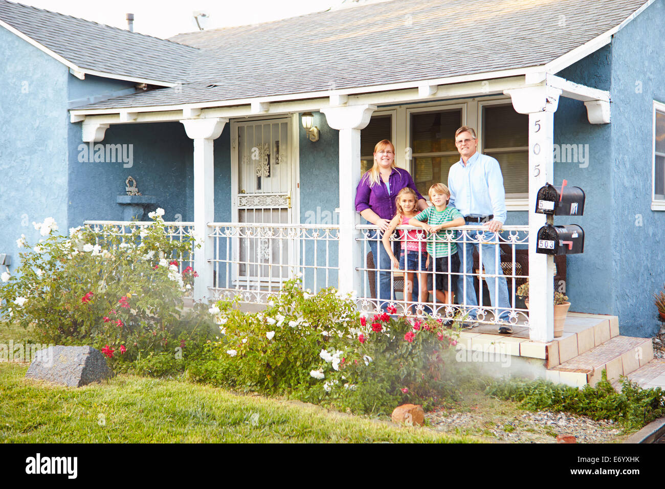 Portrait de Famille se tenant debout sur le porche de la maison de banlieue Banque D'Images
