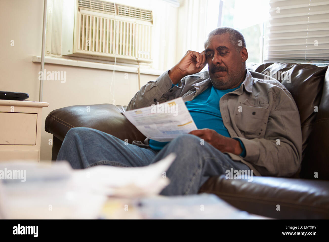 Inquiets Senior Man Sitting on Sofa à la recherche sur les projets de Banque D'Images