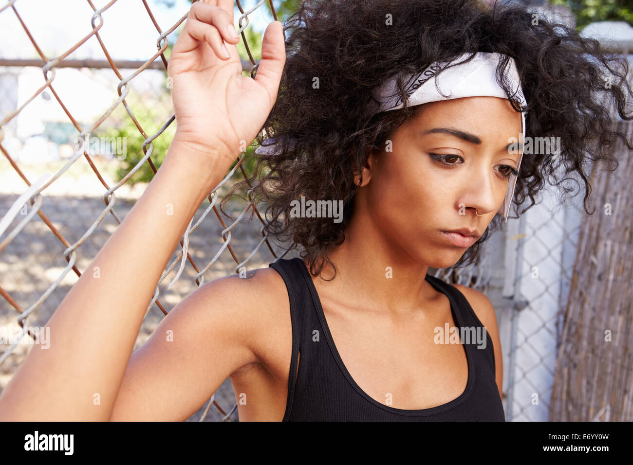 Jeune femme en milieu urbain pour Standing By Fence Banque D'Images