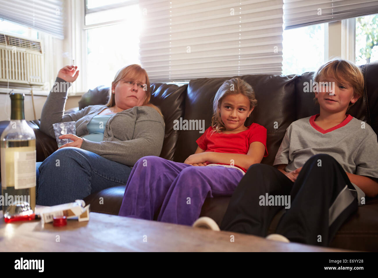 Mère est assise sur un canapé avec des enfants de fumer et de boire Banque D'Images