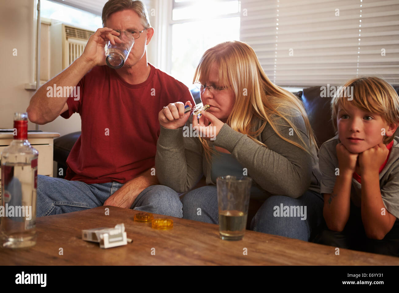Les parents s'asseoir sur le canapé avec les enfants à prendre de la drogue et l'alcool Banque D'Images