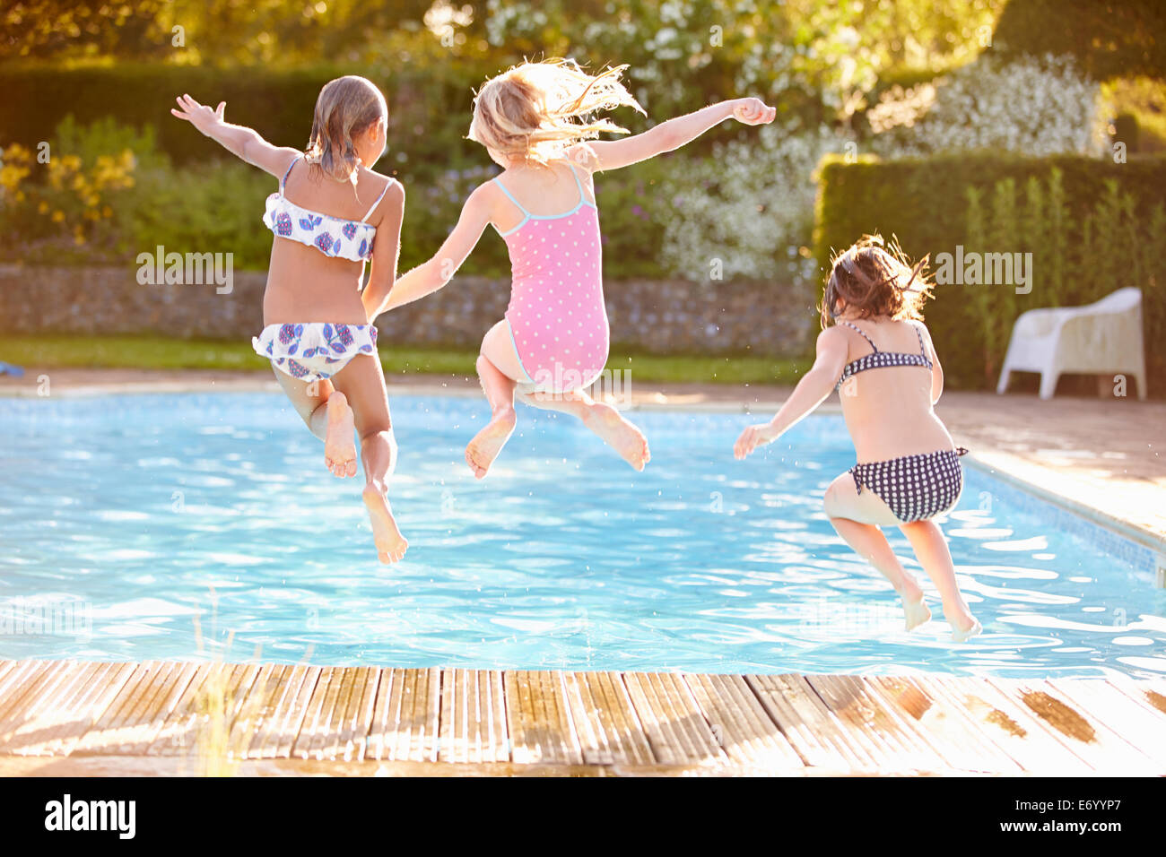 Groupe de filles sauter dans une piscine extérieure Banque D'Images