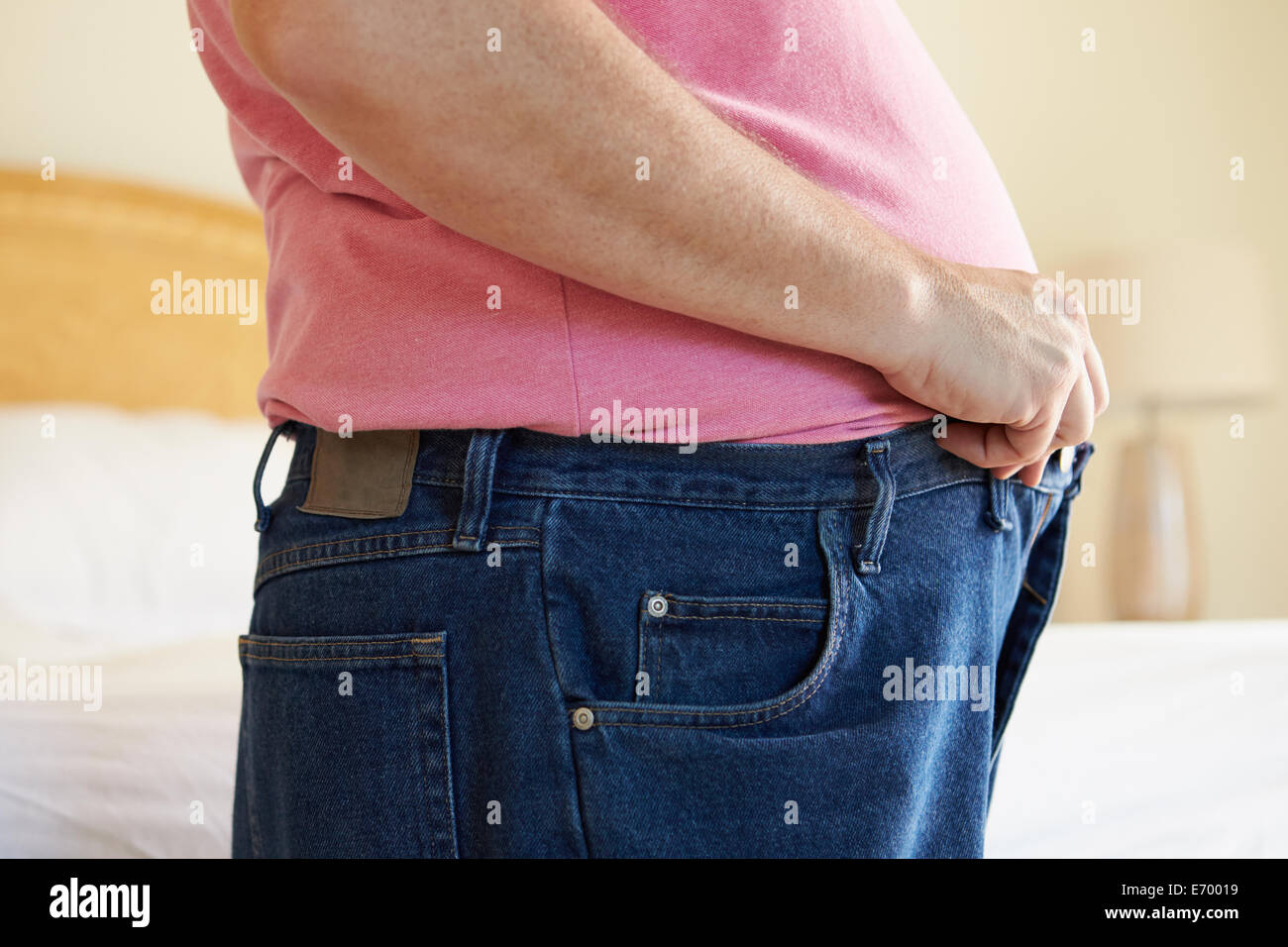 Close Up de l'excès de l'homme essayant de fixer le pantalon. Banque D'Images