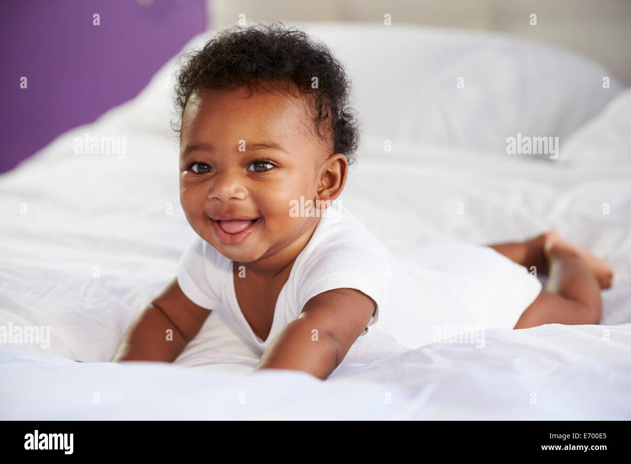 Mignon bébé couché sur le ventre dans le lit des parents Banque D'Images