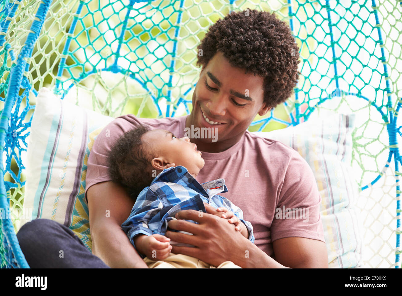 Avec Père Fils Bébé Détente sur un jardin extérieur siège pivotant Banque D'Images