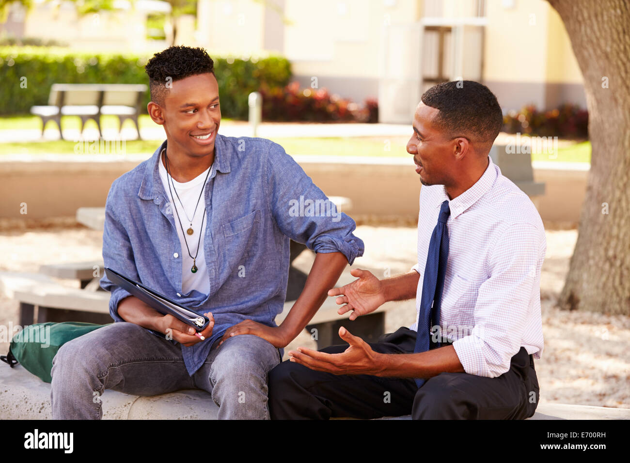 Teacher Sitting Outdoors aidant les étudiants masculins avec le travail Banque D'Images