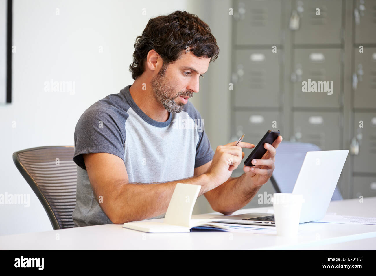 L'homme habillé en passant à l'aide de Mobile Phone In Design Studio Banque D'Images