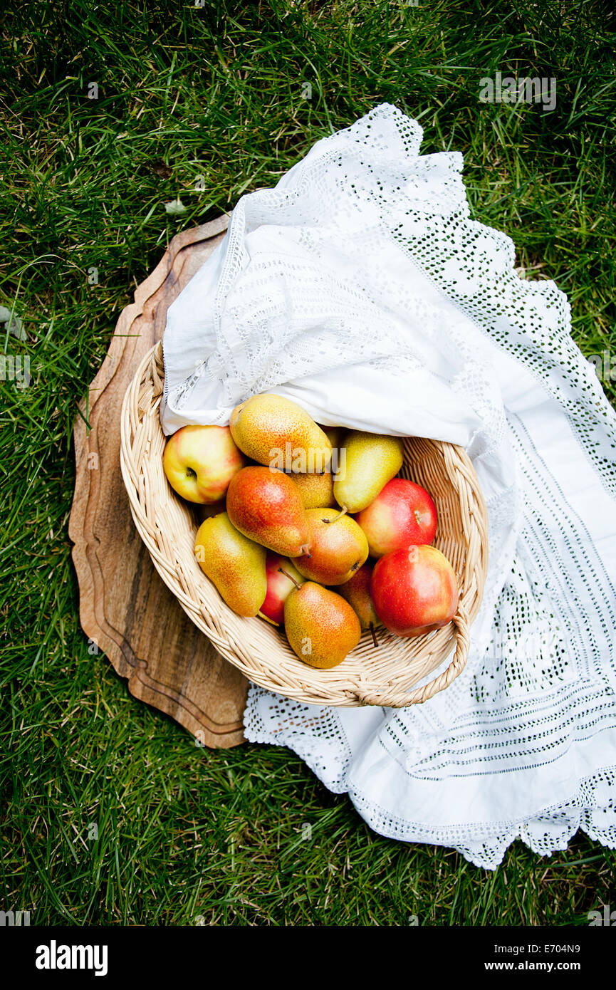 Nature morte avec panier de pommes et poires sur l'herbe Banque D'Images