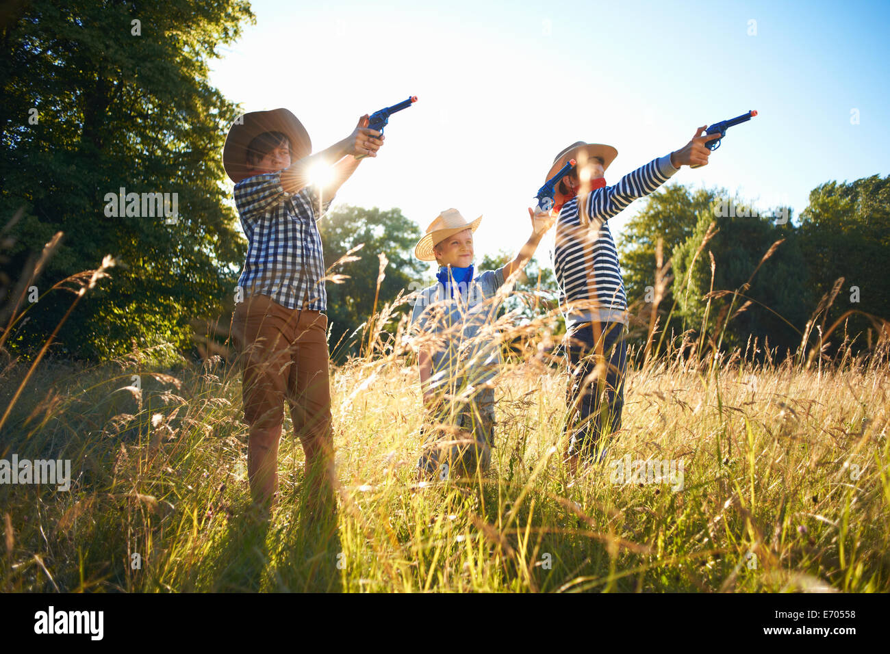 Trois jeunes garçons habillés comme des cowboys, tenant les armes-jouets Banque D'Images