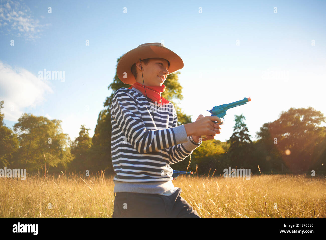 Jeune garçon habillé en cow-boy, holding toy gun Banque D'Images