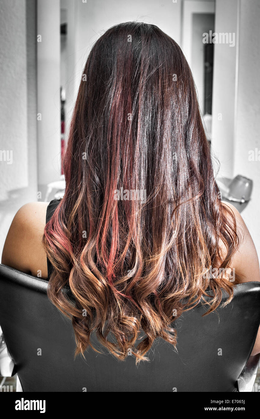 Vue arrière du jeune femme dans un salon de coiffure avec de longs cheveux brun et rose met en lumière Banque D'Images
